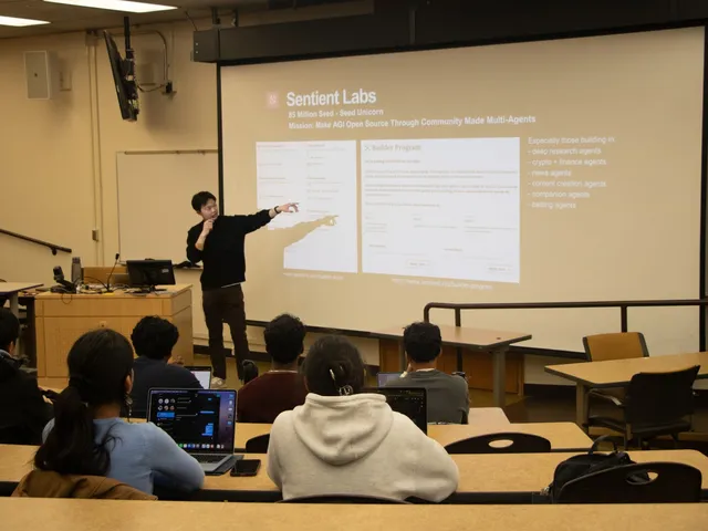 A student presenter pointing at a projected Sentient Labs slide about its builder program, seen from behind rows of students with laptops open.